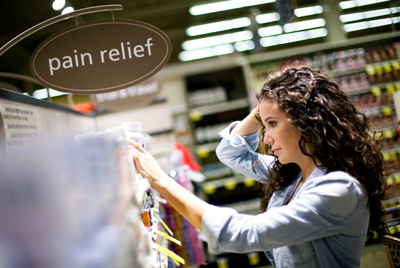 Woman with a headache reads the safety label of pain medication