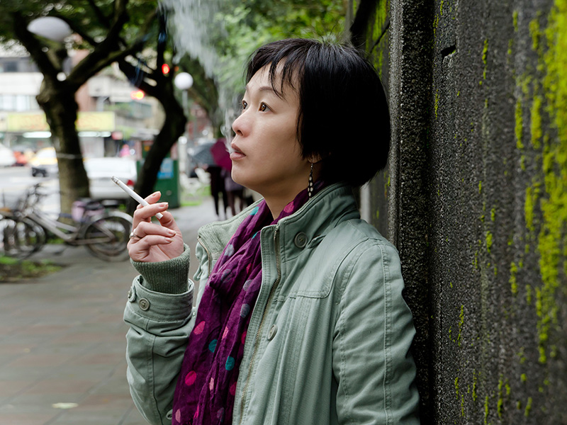 A woman in China smokes a cigarette on the sidewalk