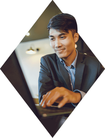 Young man in a suit using a laptop at a table.