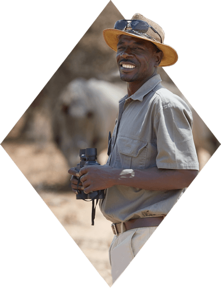 Smiling park ranger surveys rhinos with binoculars.