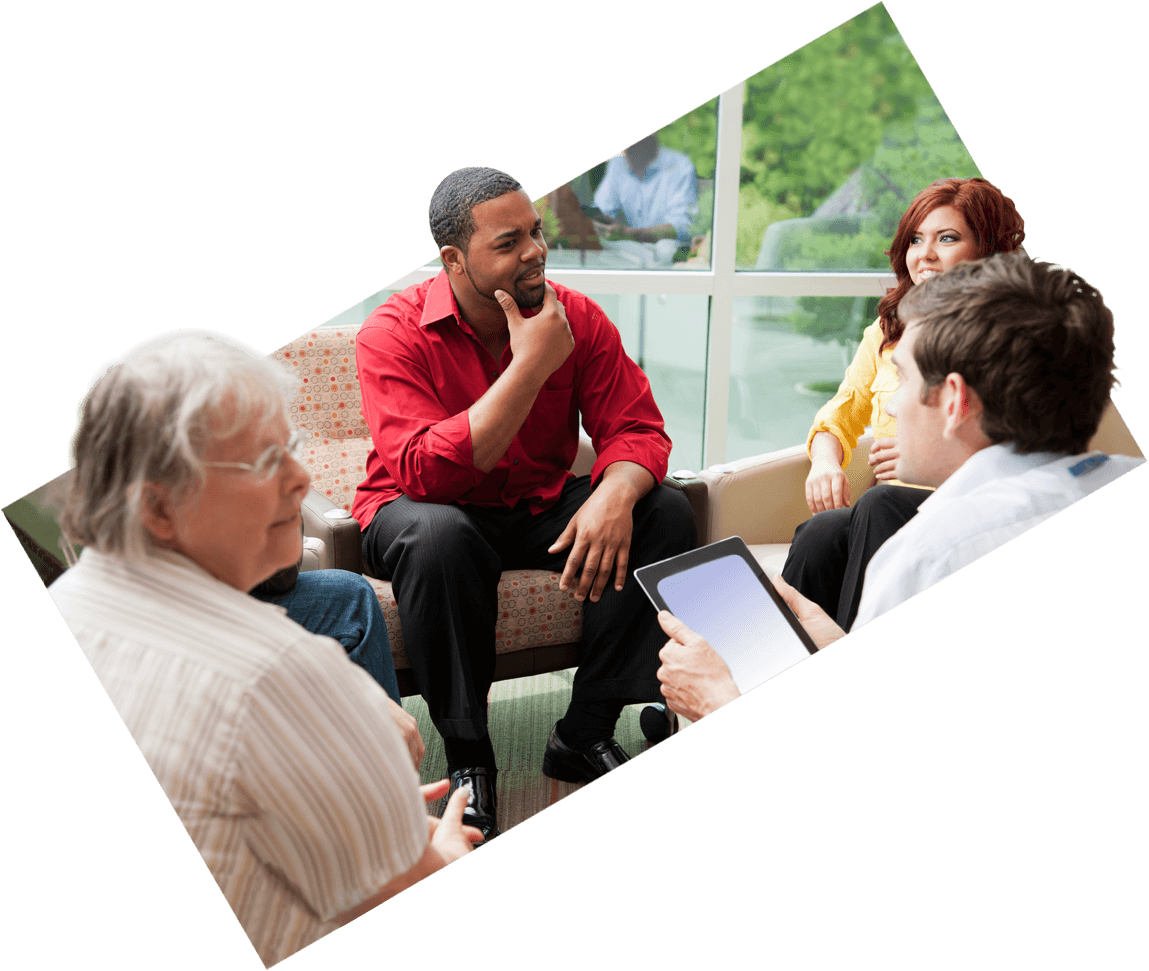 Group of people seated in a circle having a conversation in a room with large windows.