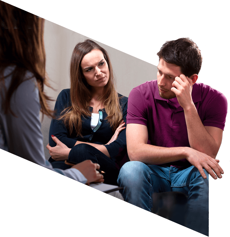 Woman and man seated beside each other on a couch, speaking to a counsellor.